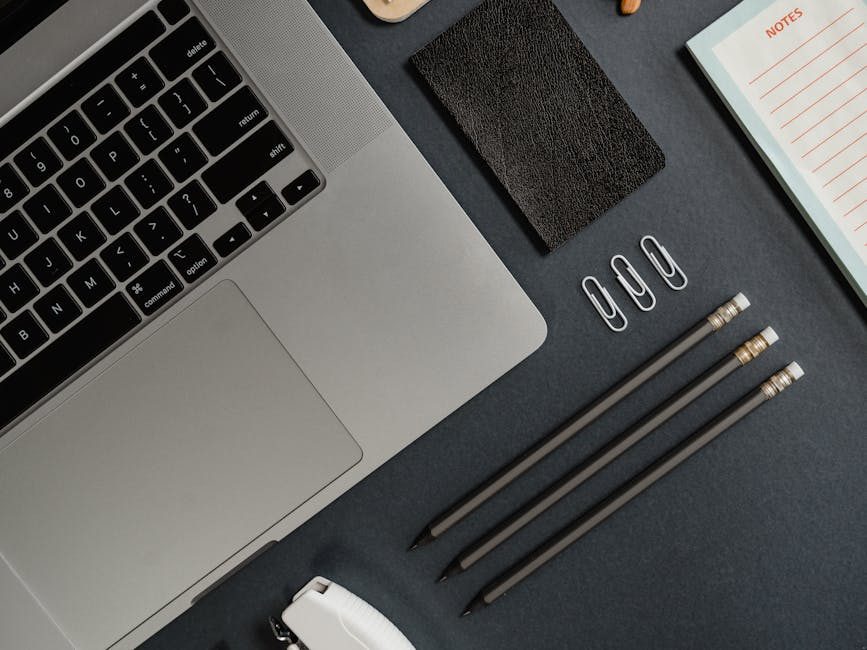 Minimalist workspace setup featuring a laptop, notebooks, and design samples for productivity