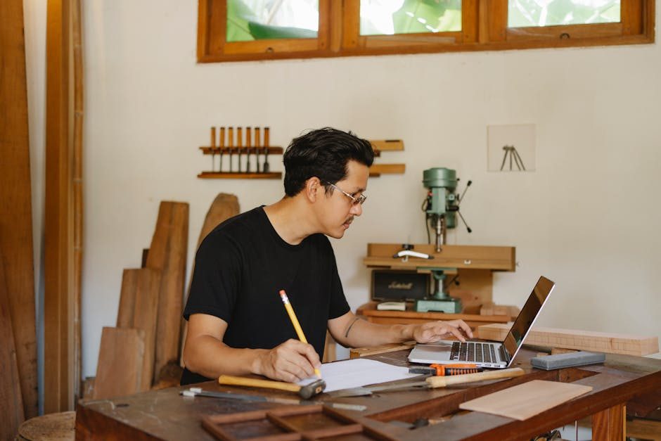 A designer working on a laptop with various design tools visible on screen