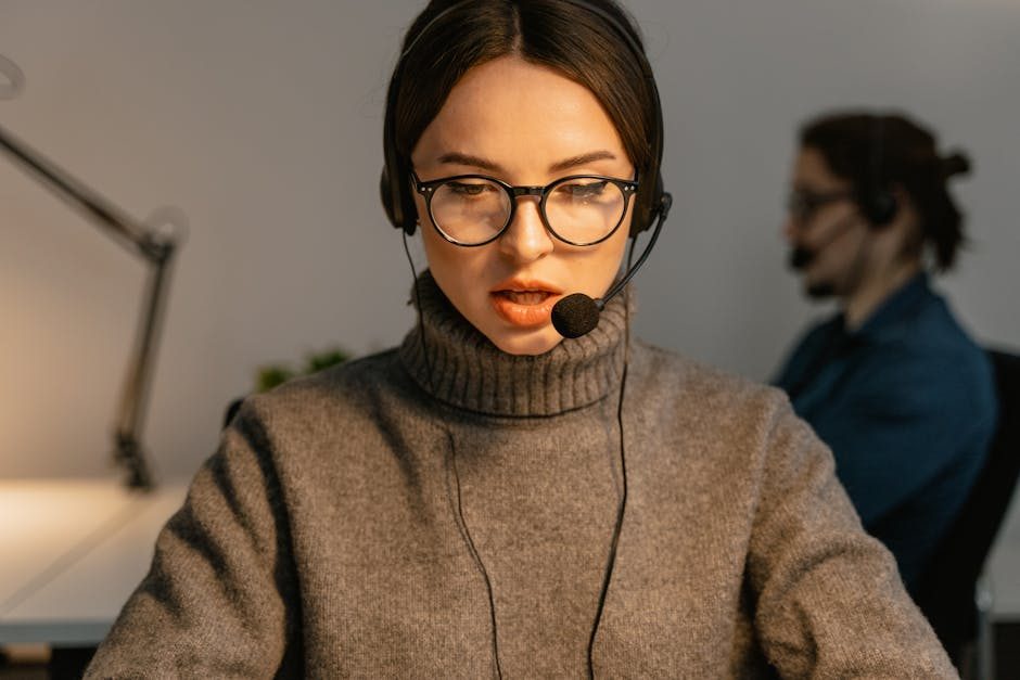 Smiling woman in headscarf working in call center on laptop with headset.