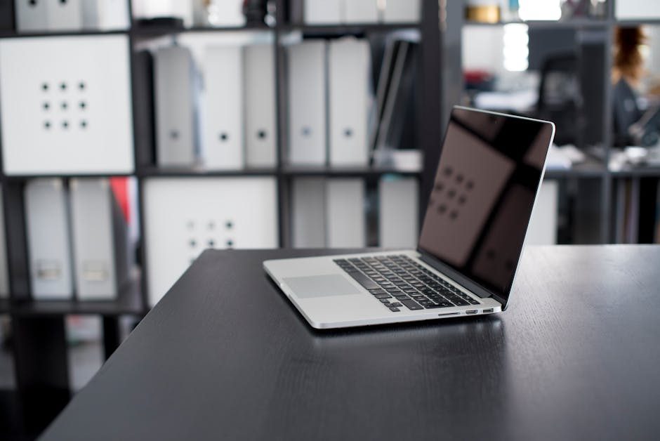 A professional man typing on a laptop in an elegant indoor office setting with a blurred background.