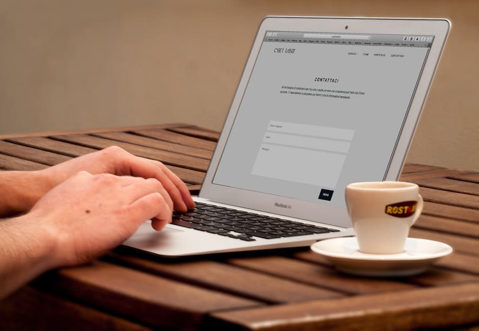 Close-up of a MacBook Pro displaying a webpage, with coffee cups and water pitcher on a table.