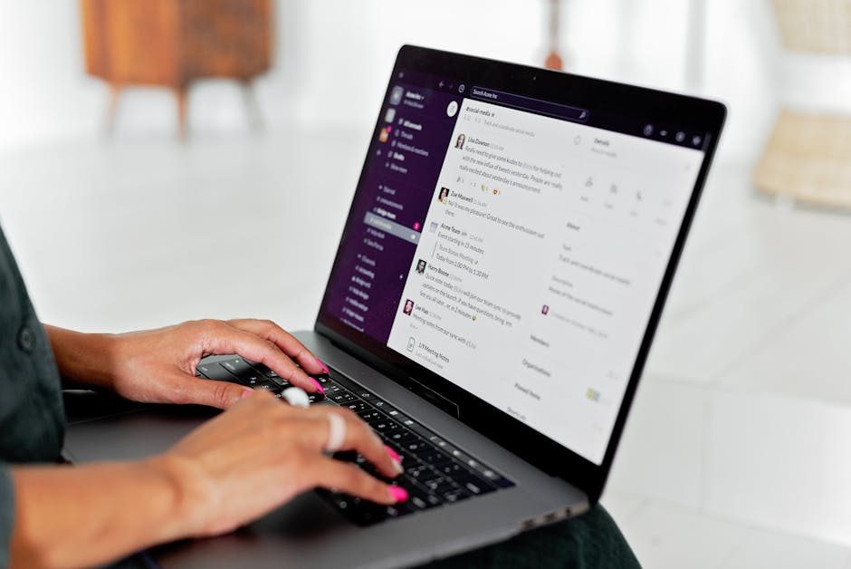Professional woman focused on her work at a desk using a laptop in a bright office setting.