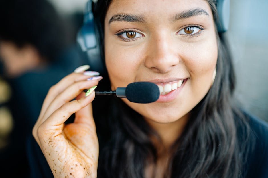 Customer support representative smiling while working alongside a friendly chatbot interface on screen.