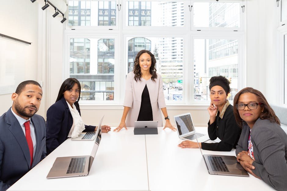 A woman in a modern office environment smiling while working on her laptop.