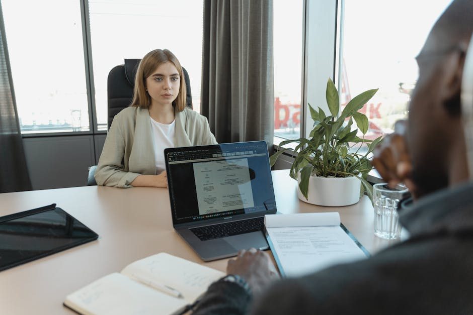 Hiring manager reviewing resumes on a laptop with coffee nearby